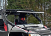 SuperATV flip-up windshield with the upper half tilted open on a red and white Arctic Cat Wildcat, helmeted driver inside