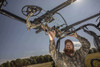 Hunter placing a camo compound bow into the Kolpin overhead in-cab gun and bow rack on a UTV roll cage