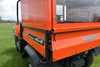 Close-up of the Wiedmann Bros bed cap glass door above the tailgate of the orange Kubota RTV