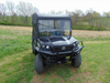 Front view of a black Kubota RTV XG850 with the 3 Star soft top and full cab installed, parked in a grassy field