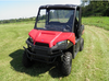 Driver side front angle of a red Polaris Ranger 570 MidSize in a field with the 3 Star one-piece windshield