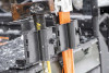 Kolpin chainsaw mount holding an orange chainsaw and a splitting maul on a side-by-side bed rail in falling snow