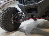 Front corner view of the Trail Armor arm guard under a Polaris RZR Pro R front A-arm beside the knobby tire