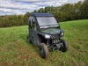 Green Honda Pioneer 500 with the 3 Star full cab enclosure installed, front three-quarter view on a hillside