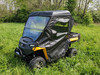 Driver side front view of the 3 Star full cab enclosure on a Cub Cadet Challenger 400 in a grassy field