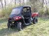 3 Star vinyl windshield and top combo on a red Can-Am Defender, front three-quarter view in a field by trees
