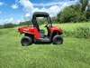 3 Star soft top for hard windshield on a red Arctic Cat Prowler 500, driver side profile in a green field