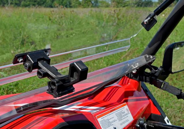 Close-up of the black hinge latch on the SuperATV flip out windshield above the red CF Moto ZForce hood