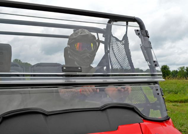 Passenger side front view of the SuperATV flip out windshield tilted open on the red Honda Pioneer 700