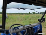 Driver seat view through the SuperATV flip-up windshield tilted open above the Polaris Ranger XP dash