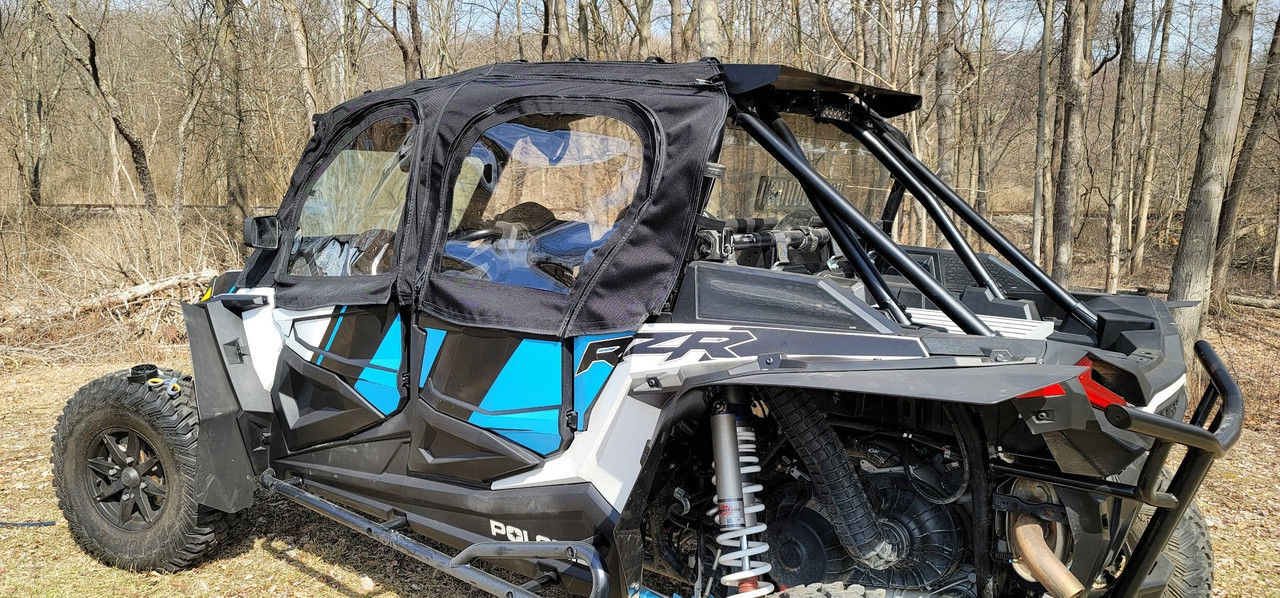 Rear three-quarter view of the Side X Side upper doors on the blue and white Polaris RZR S4 by the trees