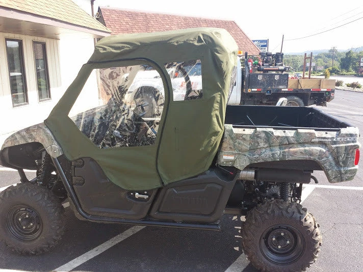 Side X Side full cab enclosure in green on a camo Yamaha Viking parked in a dealership lot, side view