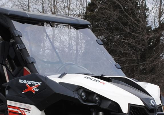 SuperATV full windshield installed on a white and red Can-Am Maverick, front three-quarter view with bare trees
