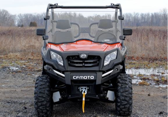 Straight-on front view of the orange CF Moto U-Force 800 with the SuperATV full windshield on a winter field