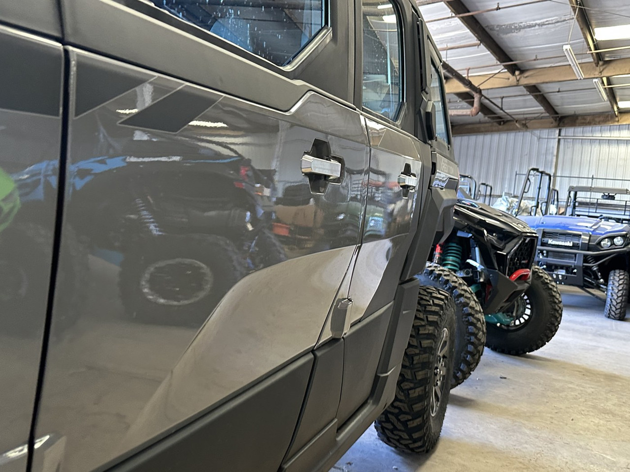 Dirty Teeth Racing billet aluminum exterior door handles installed on a gray Polaris Xpedition, side view in a shop