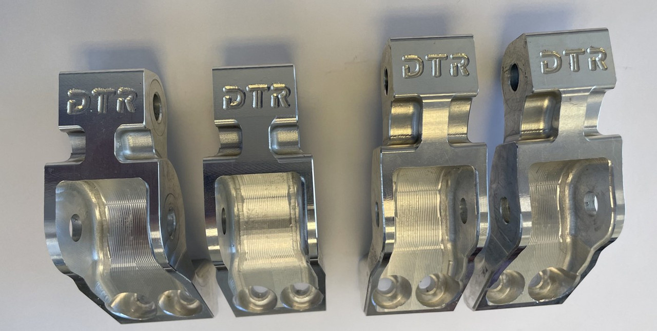 Four raw machined aluminum Dirty Teeth Racing lift brackets stamped DTR before black finishing