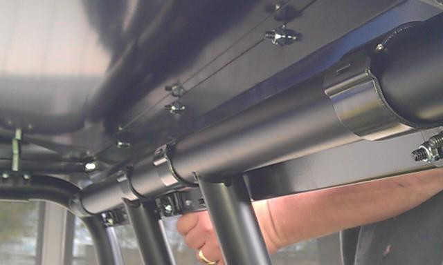 Close-up under the Extreme Metal Products hard roof showing the clamp brackets on the Ranger Crew cage tubes