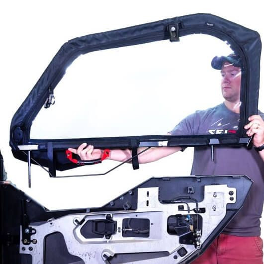 Person lifting a Seizmik framed upper door with clear window onto a Polaris General lower door