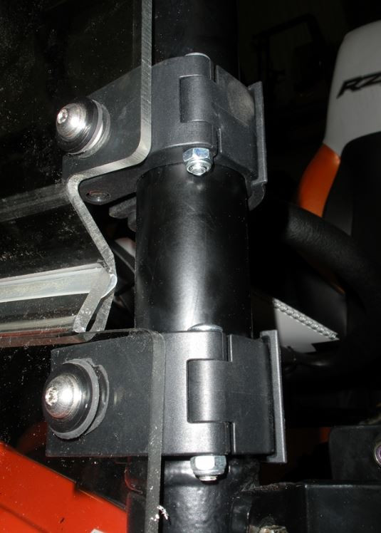 Close-up of the Trail Armor windshield clamp bracket bolted to a roll cage tube on a side-by-side