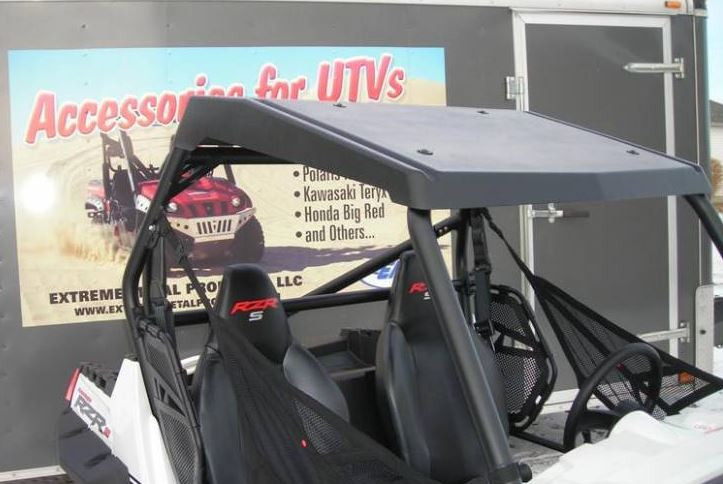 Rear three-quarter view of the Extreme Metal Products hard top on a white Polaris RZR in front of a trailer