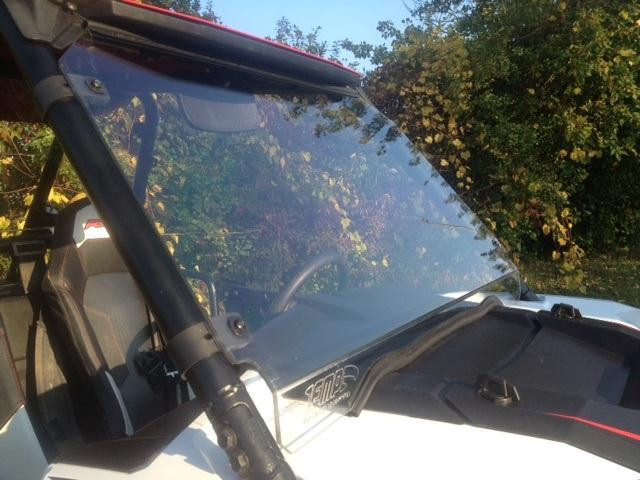 Extreme Metal Products full windshield on a white Polaris RZR, side view with the cage clamp and autumn trees