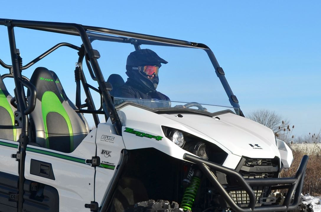 SuperATV scratch resistant full windshield on a white Kawasaki Teryx with a driver, front three-quarter view