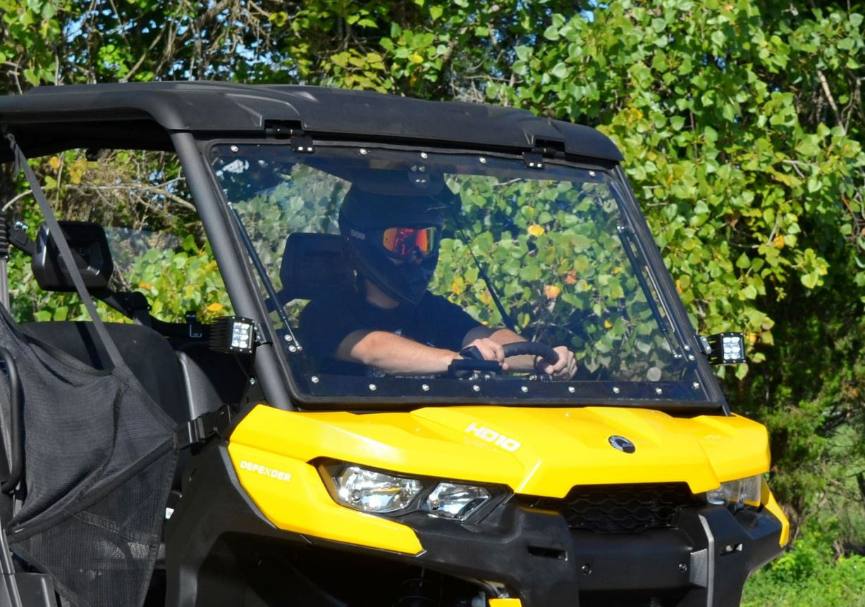 Front three-quarter close view of the SuperATV windshield closed on the yellow Can Am Defender with driver behind it