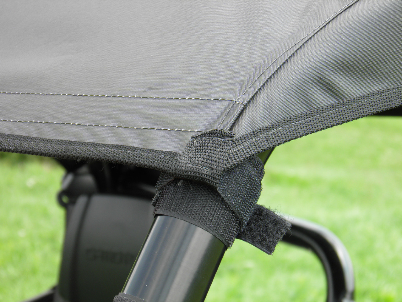 Close-up of the 3 Star cab enclosure roof corner strapped to the CFMoto UForce cage tube