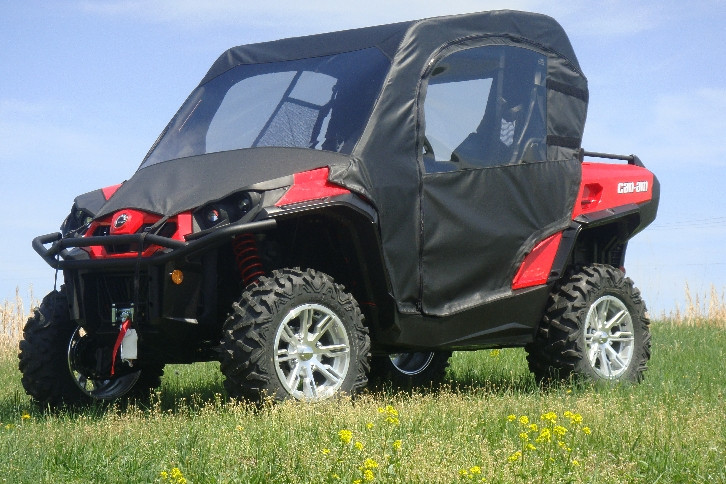 Red CanAm Commander with the 3 Star full cab enclosure installed, front three-quarter view in tall grass