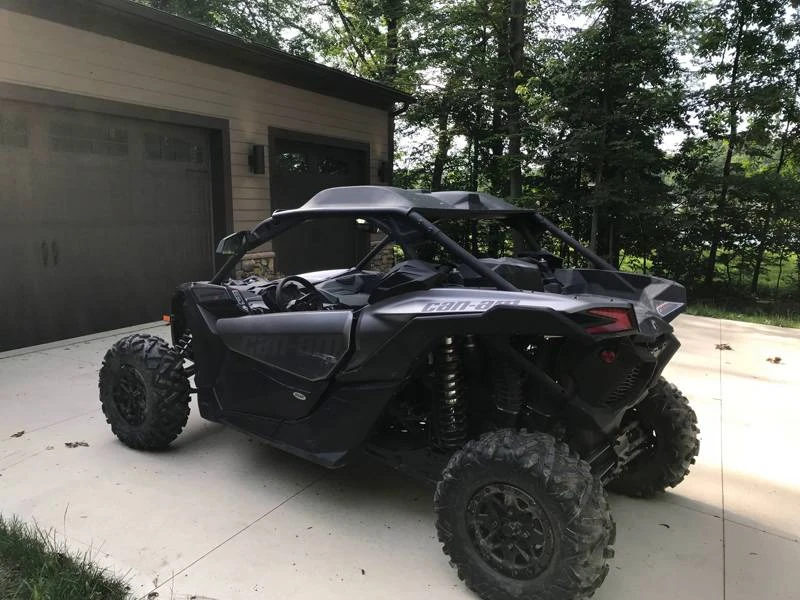 Black Can-Am Maverick X3 with the Extreme Metal Products roof parked on a driveway, front three-quarter view