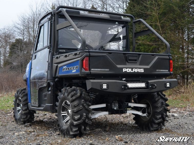 Rear three-quarter view of the blue Ranger with the SuperATV rear bumper and cab on a gravel road