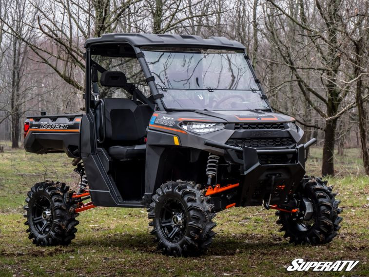 SuperATV 4 inch portal gear lift on a gray side-by-side with cab, roof and mud tires, front three-quarter view