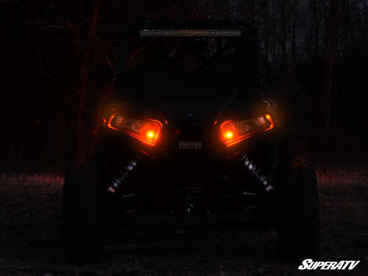 Straight front view of a side-by-side at night with both SuperATV amber turn signals glowing