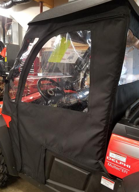 Side X Side full cab enclosure on a red Hisun Sector 450, black soft doors with clear windows, side view in a shop