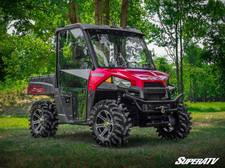 Red Polaris Ranger Midsize with SuperATV cab doors installed, front three-quarter view in the woods