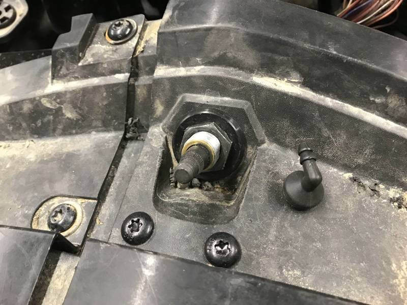 EMP wiper pivot shaft and washer nozzle fitted through a black plastic panel of a CanAm Maverick X3