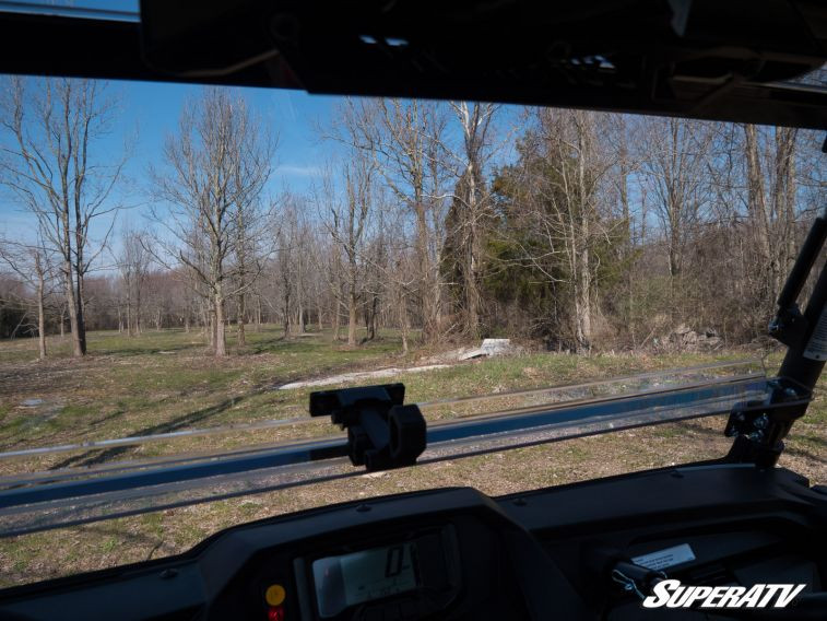 View from the driver seat through the SuperATV flip windshield tilted open on a Yamaha Wolverine, trees ahead