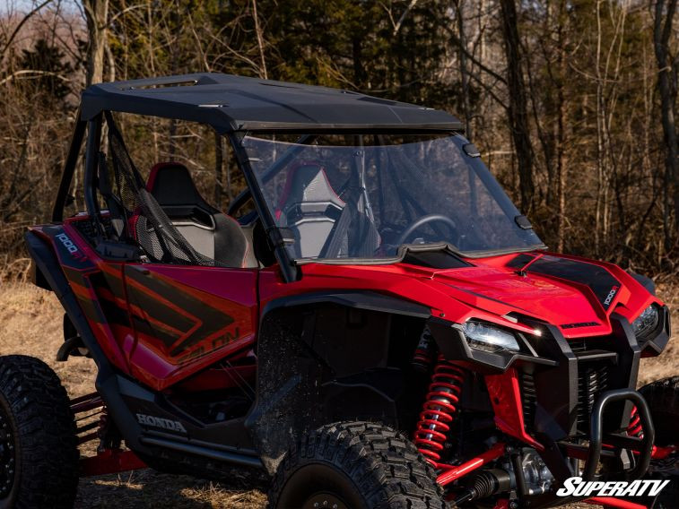 Passenger side angle of the Honda Talon 1000 with the SuperATV full windshield and roof, trees behind