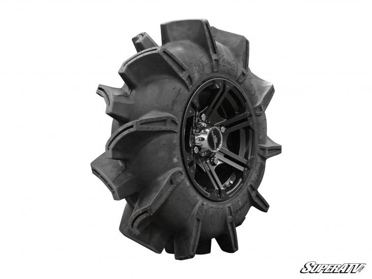 SuperATV Assassinator mud tire mounted on a black wheel, side view showing tall paddle-style tread lugs