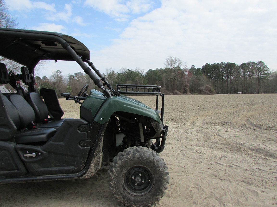 Side view of a green Yamaha Viking VI in a field showing the Seizmik hood rack mounted above the hood