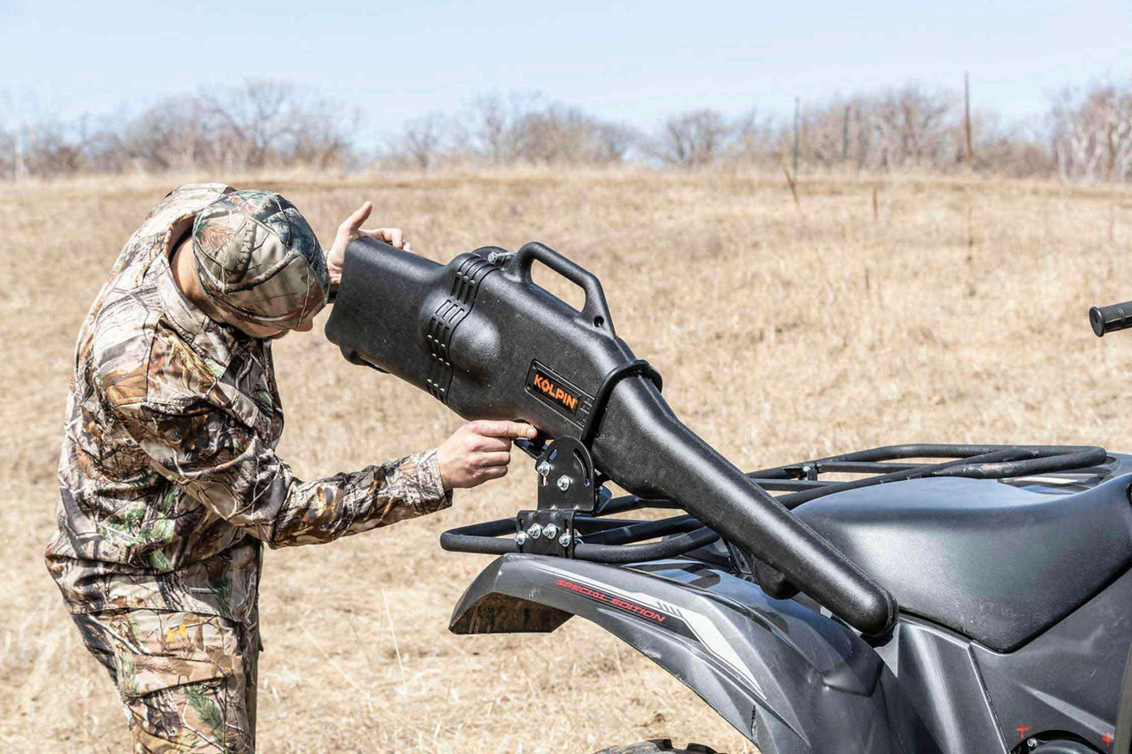 Hunter sliding a gun boot into a Kolpin loop bracket on the rear rack of an ATV