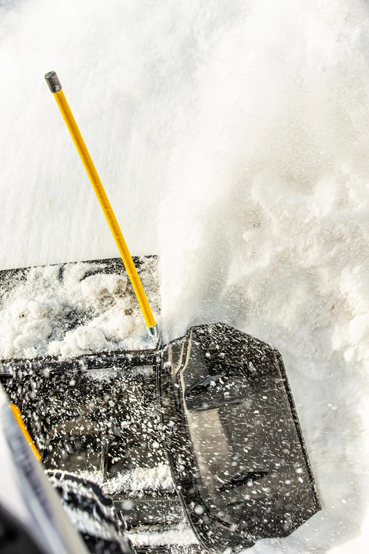 Kolpin snow plow blade wing on a black plow pushing snow, close-up with yellow marker pole