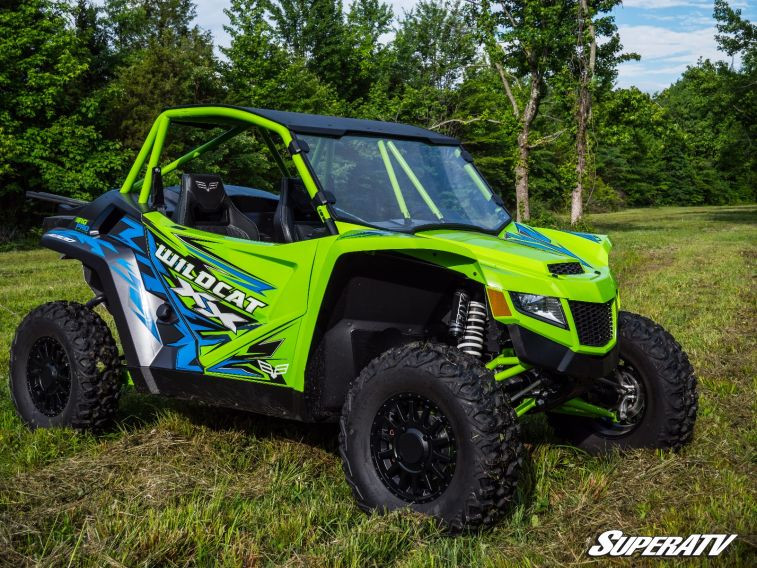Side three-quarter view of a green Textron Wildcat XX with the SuperATV full windshield and roof on grass
