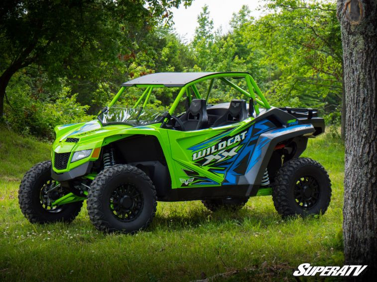 Front three-quarter view of the green Textron Wildcat XX in the woods with the SuperATV half windshield