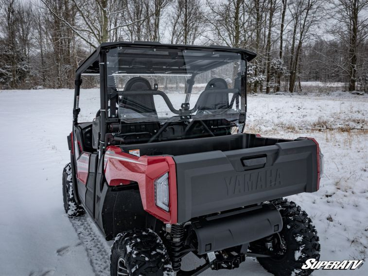 Rear view of the red Yamaha Wolverine X2 in snow with the SuperATV rear windshield above the dump bed