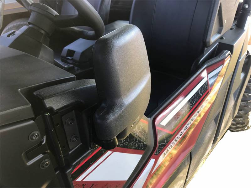 Folding side mirror in the folded position on the red Yamaha Wolverine door, seen from the rear quarter