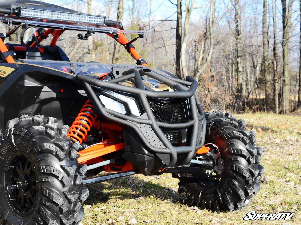 SuperATV front bumper installed on an orange and black Can-Am Maverick X3 in a field, front three-quarter view