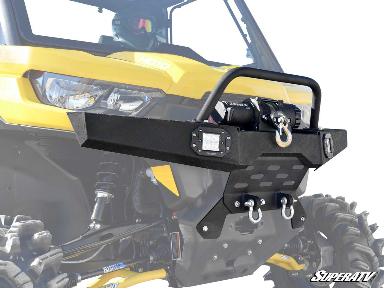 SuperATV diamond plate front bumper with winch and D-ring shackles on a yellow Can-Am Defender, front three-quarter close-up