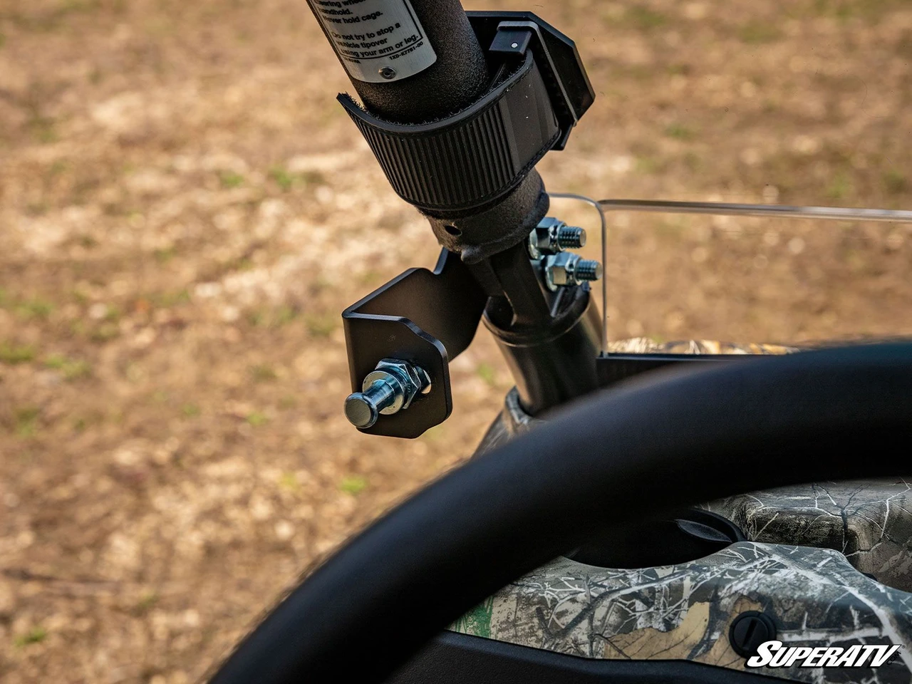 Close-up of the SuperATV enclosure mounting bracket clamped to the Yamaha Viking cage at the windshield edge