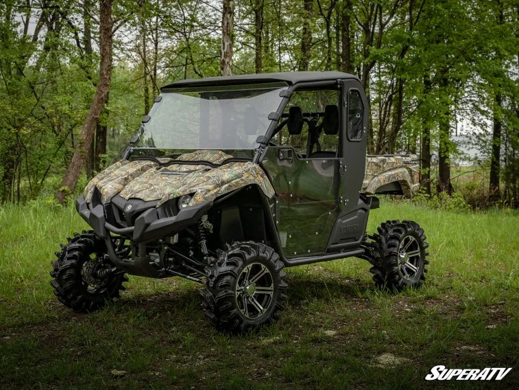 Front three-quarter view of the camo Yamaha Viking with SuperATV hard doors and enclosure in green woods